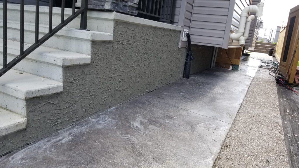 Concrete steps leading to a building, featuring a textured polymer-modified cement parging finish on the foundation wall, illustrating durability and aesthetic enhancement for construction.