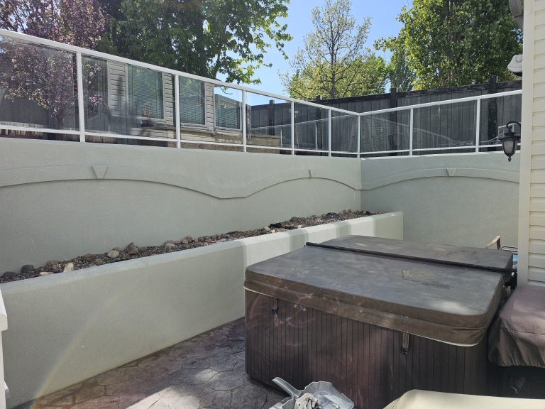 Acrylic parging installation in outdoor space featuring a hot tub, decorative wall design, and glass railing, illustrating aesthetic enhancement and moisture protection.