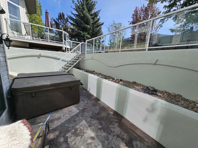 Acrylic parging installation in outdoor space, featuring a hot tub, decorative wall with a smooth finish, and landscaped area, emphasizing aesthetic appeal and durability.